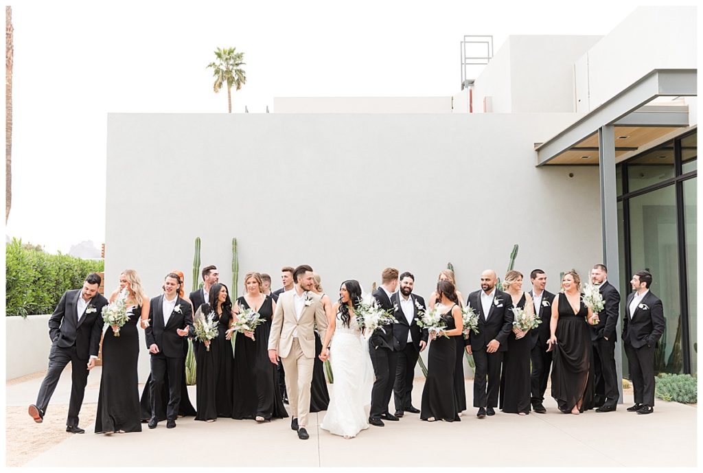 A large wedding party dressed in black walking towards the camera at Andaz Scottsdale