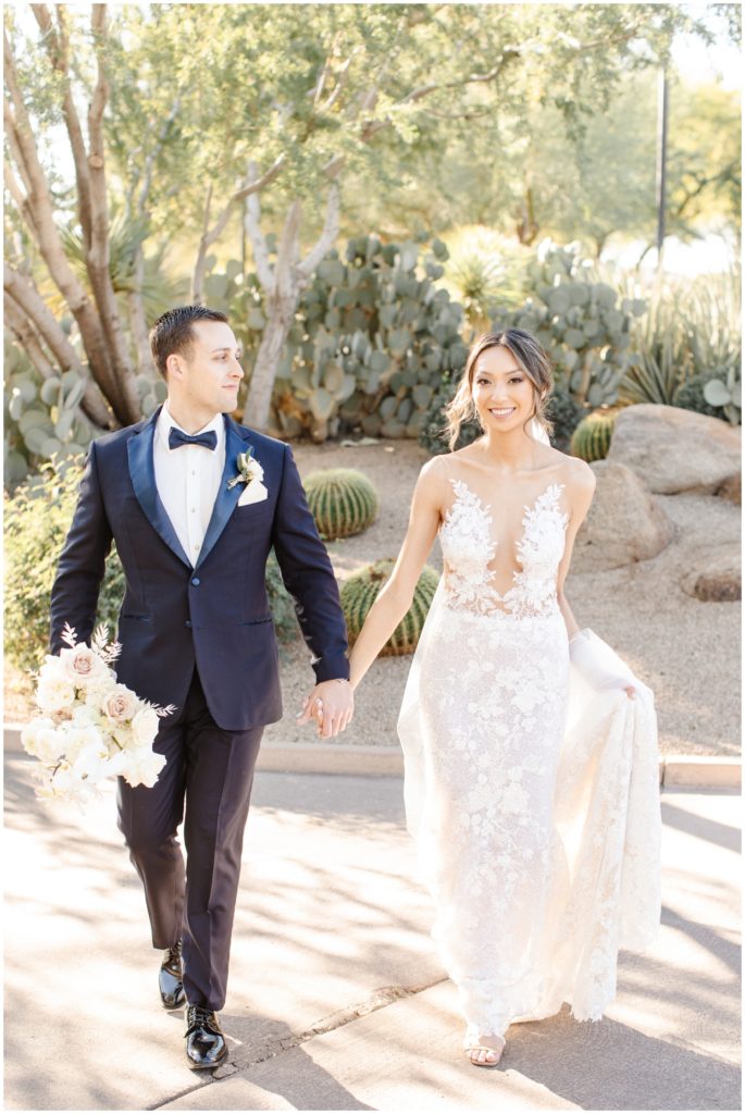 bride and groom walk towards camera with cacti behind them at westin kierland on their wedding day